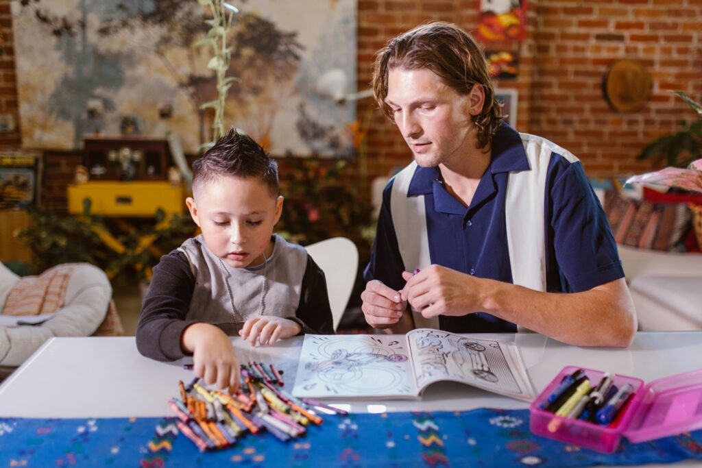 Child engaged in coloring activity at home with adult supervision, fostering creativity.